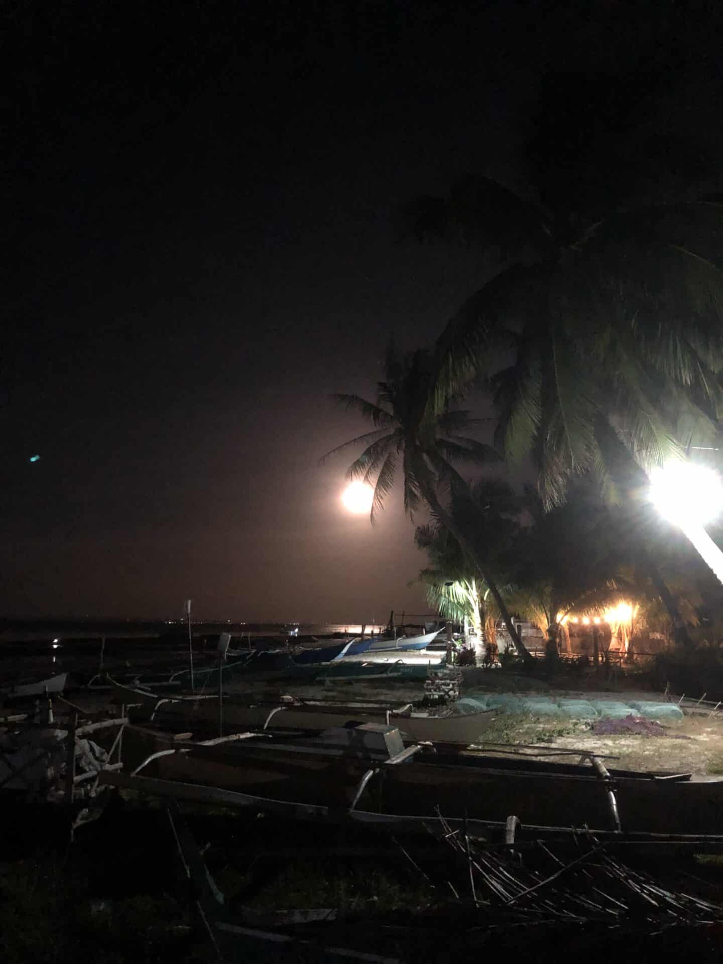 Fishing boats sitting on the beach at night.