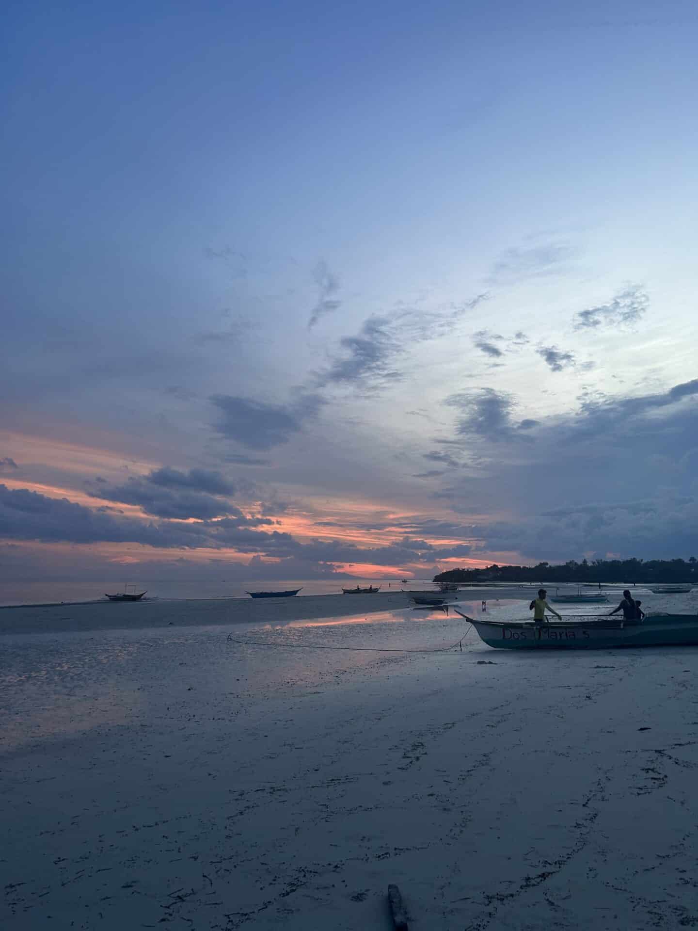 A beach with fishing boats mooring at sunset.