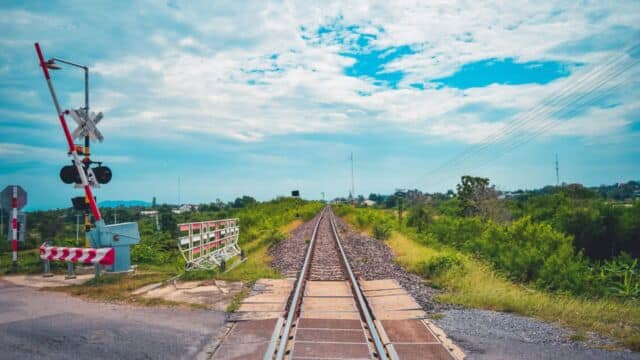 Railway crossing with green surrounds and partly cloudy sky