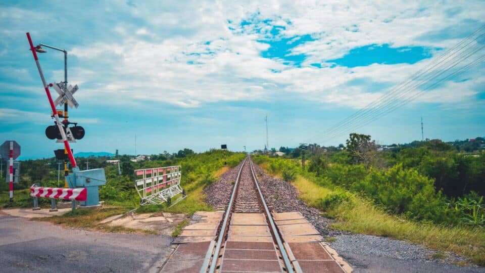 Railway crossing with green surrounds and partly cloudy sky