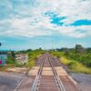 Railway crossing with green surrounds and partly cloudy sky